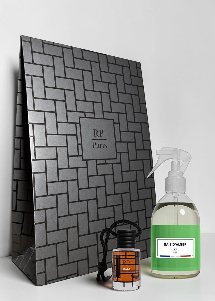 A gift set featuring a large dark gray patterned box with a central 'RP Paris' logo, a small clear bottle with an orange label and black cap, and a clear spray bottle with a green label reading 'BAIE D'ALGER'.