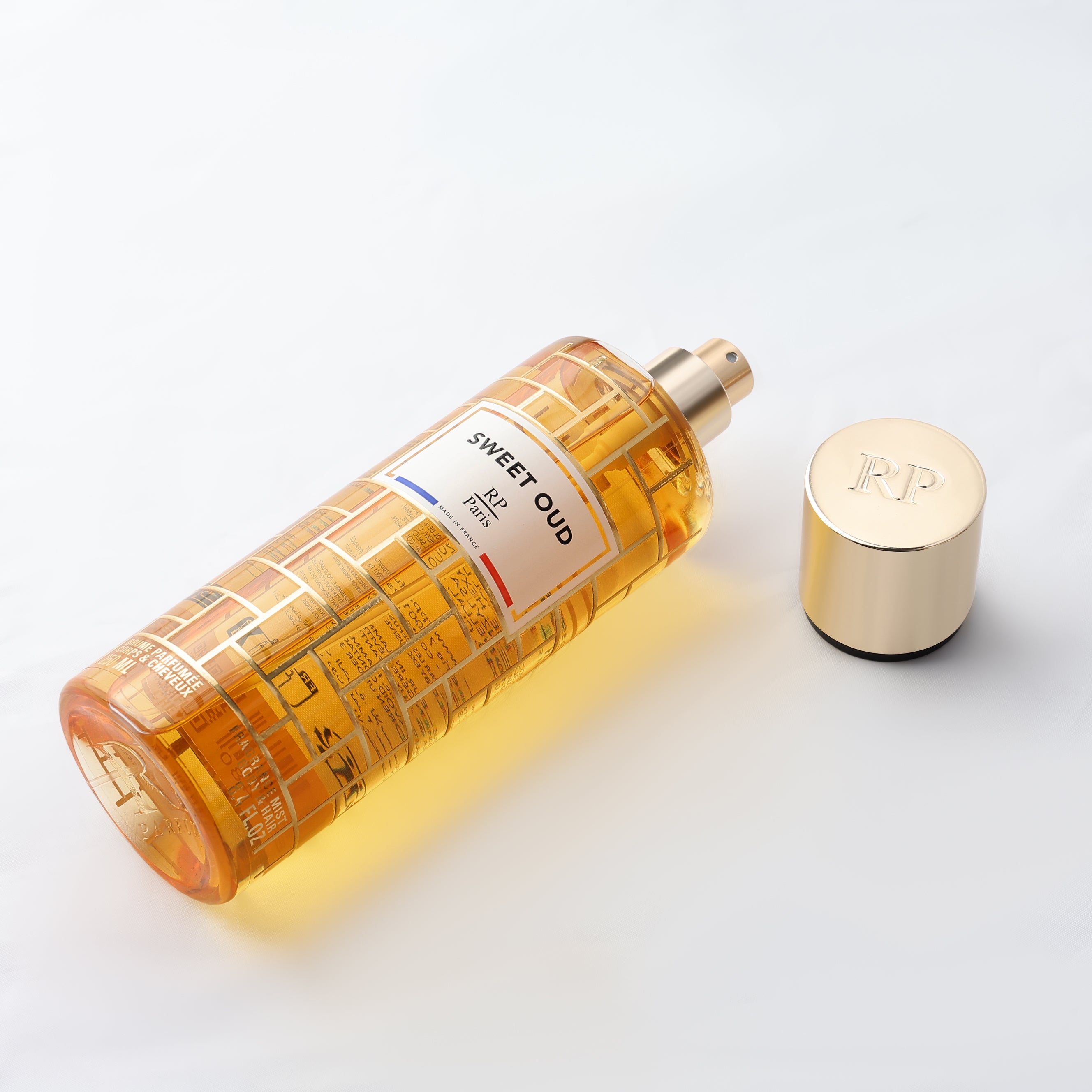 Perfume bottle labeled 'Sweet Oud' with a gold cap on a light background