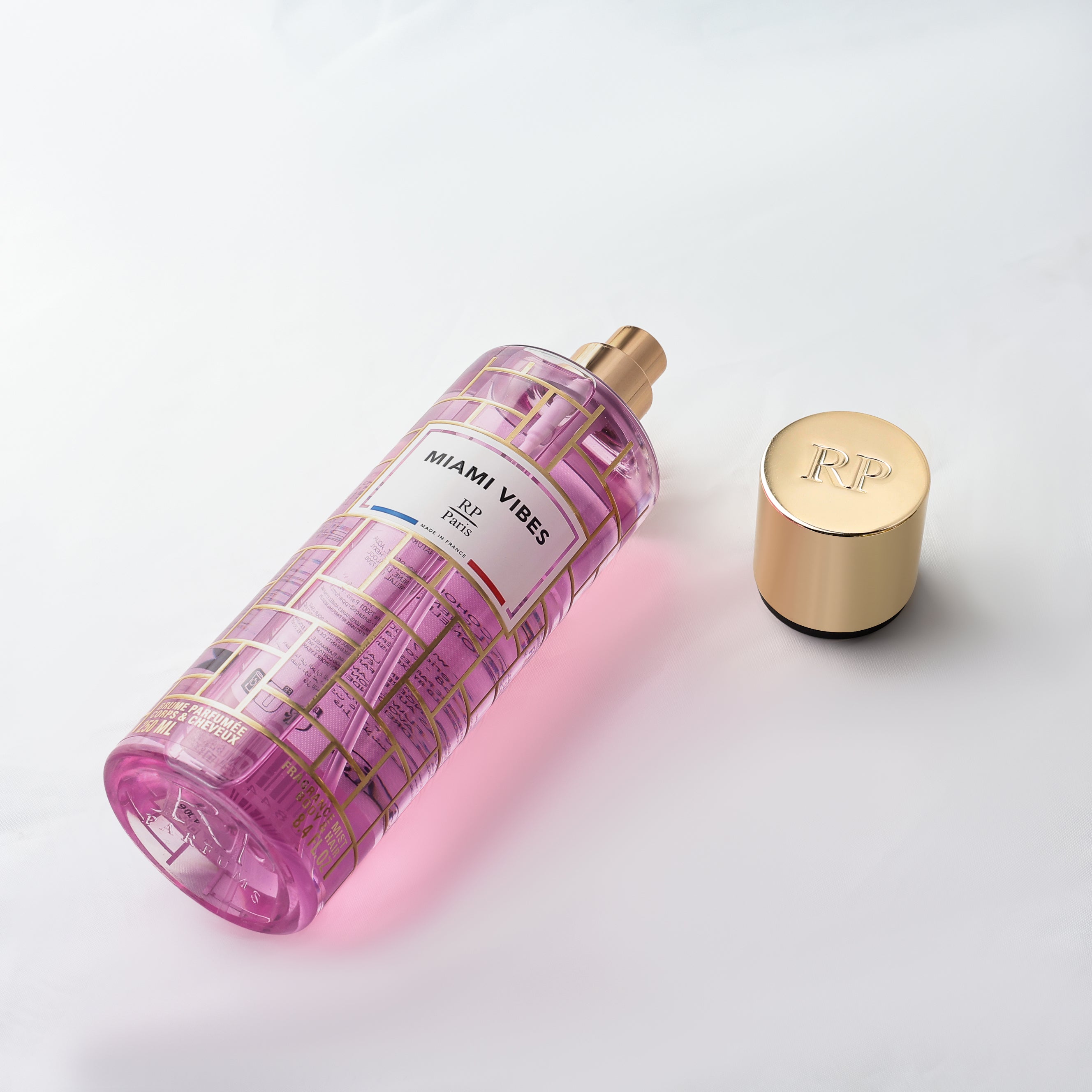 Pink perfume bottle with gold cap on a light gray background