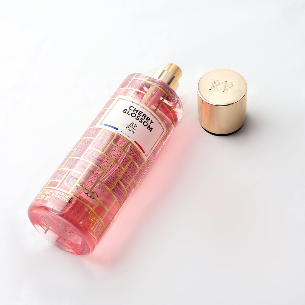 Pink bottle of Cherry Blossom perfume with gold cap on a white background