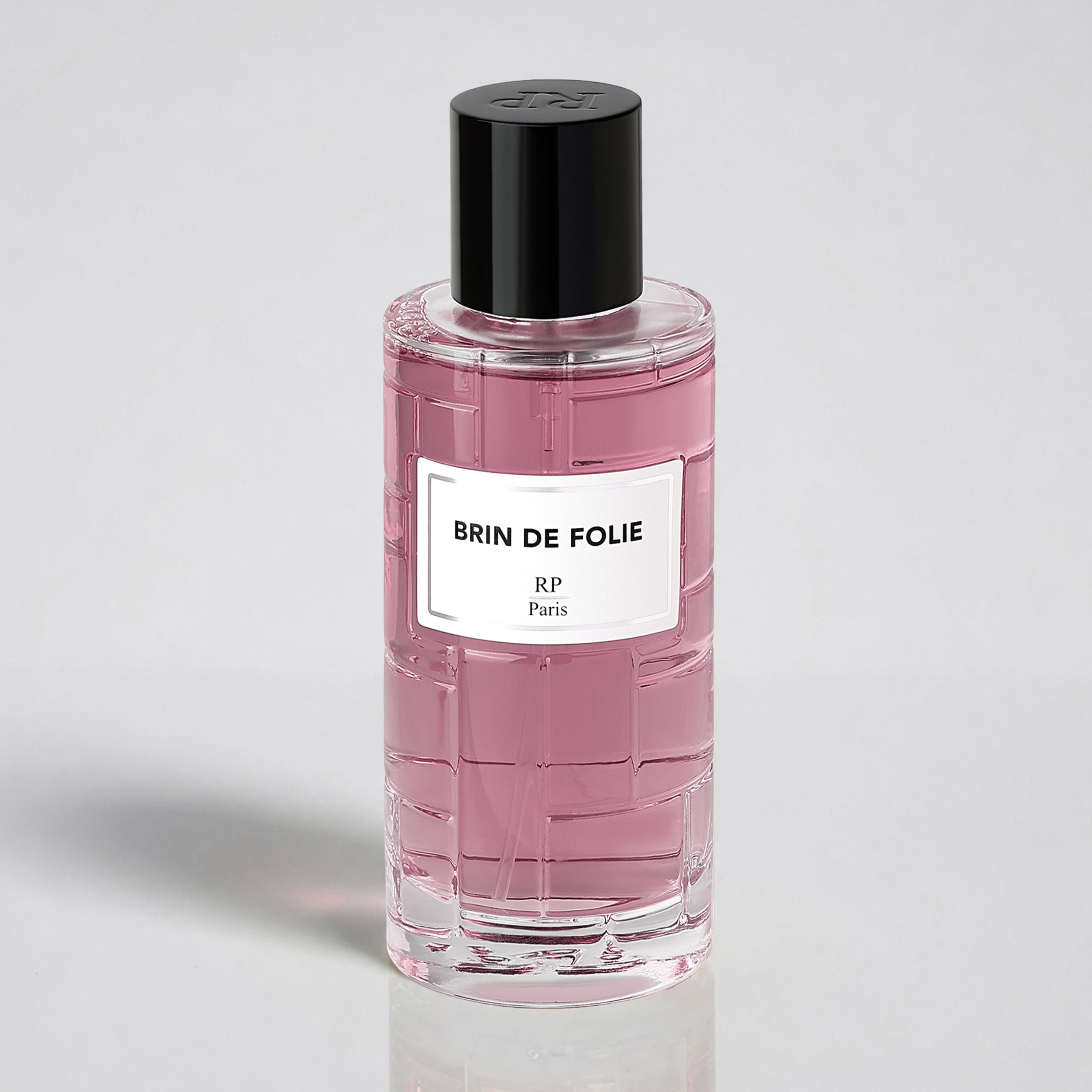 Pink perfume bottle with black cap and white label on a light gray background