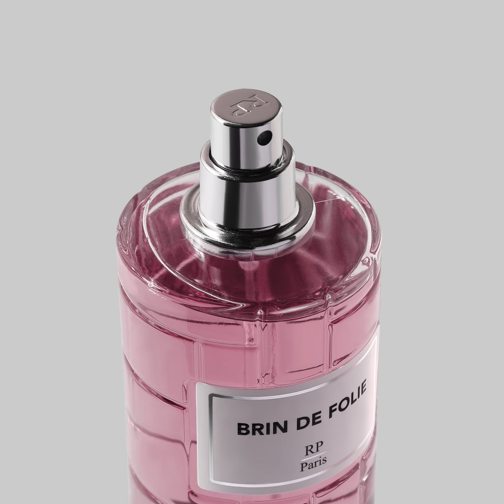 Pink perfume bottle with silver cap on a gray background