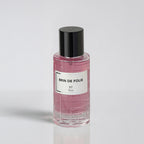 Pink perfume bottle with black cap on a light gray background