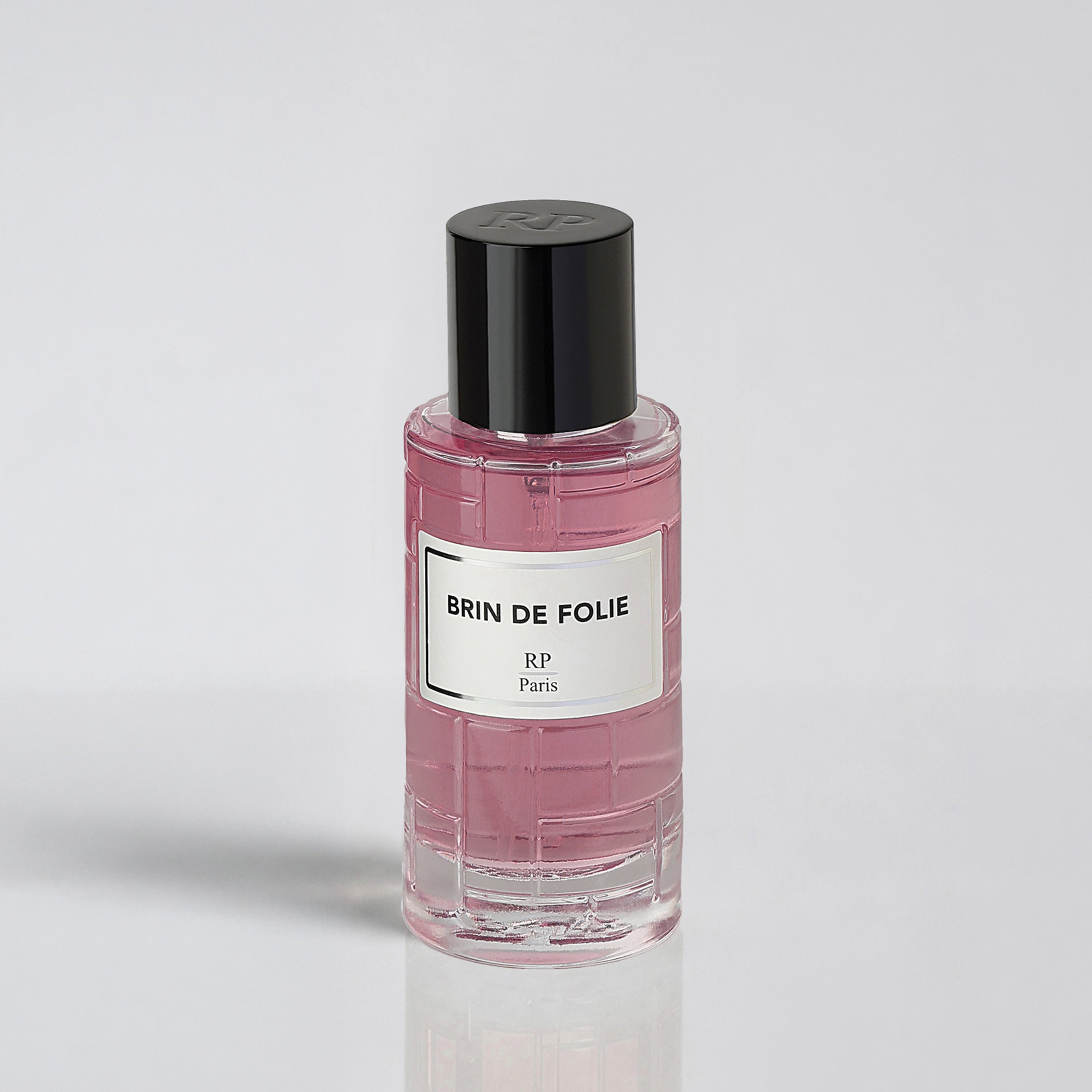 Pink perfume bottle with black cap on a light gray background