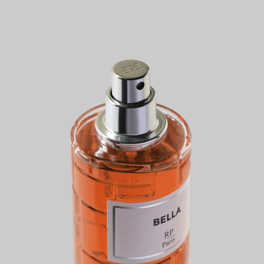 Perfume bottle labeled 'Bella' with a silver cap on a gray background