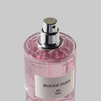 Pink perfume bottle with silver cap on a light gray background