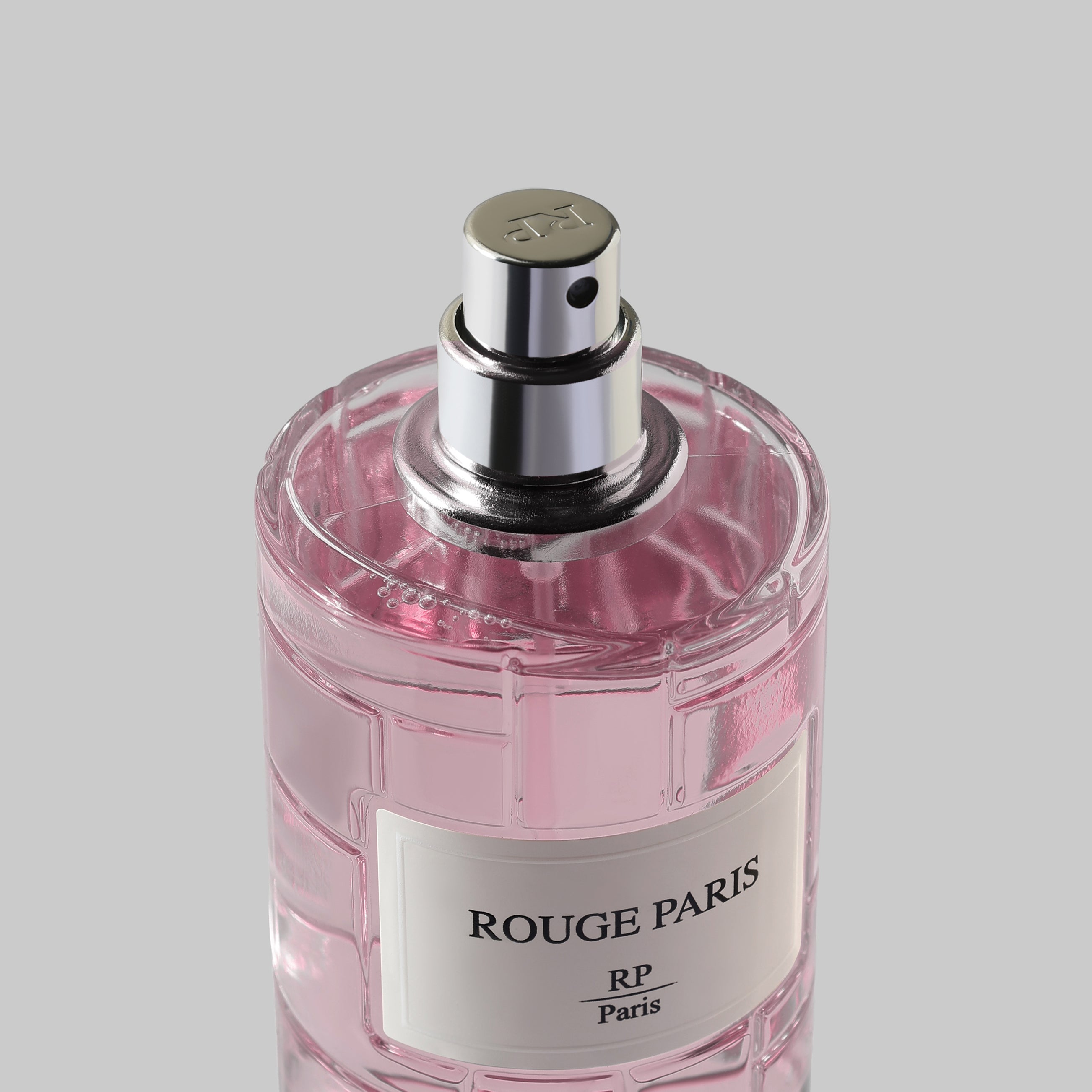 Pink perfume bottle with silver cap on a light gray background