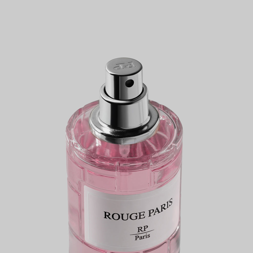 Pink perfume bottle with silver cap labeled 'Rouge Paris' on a light gray background