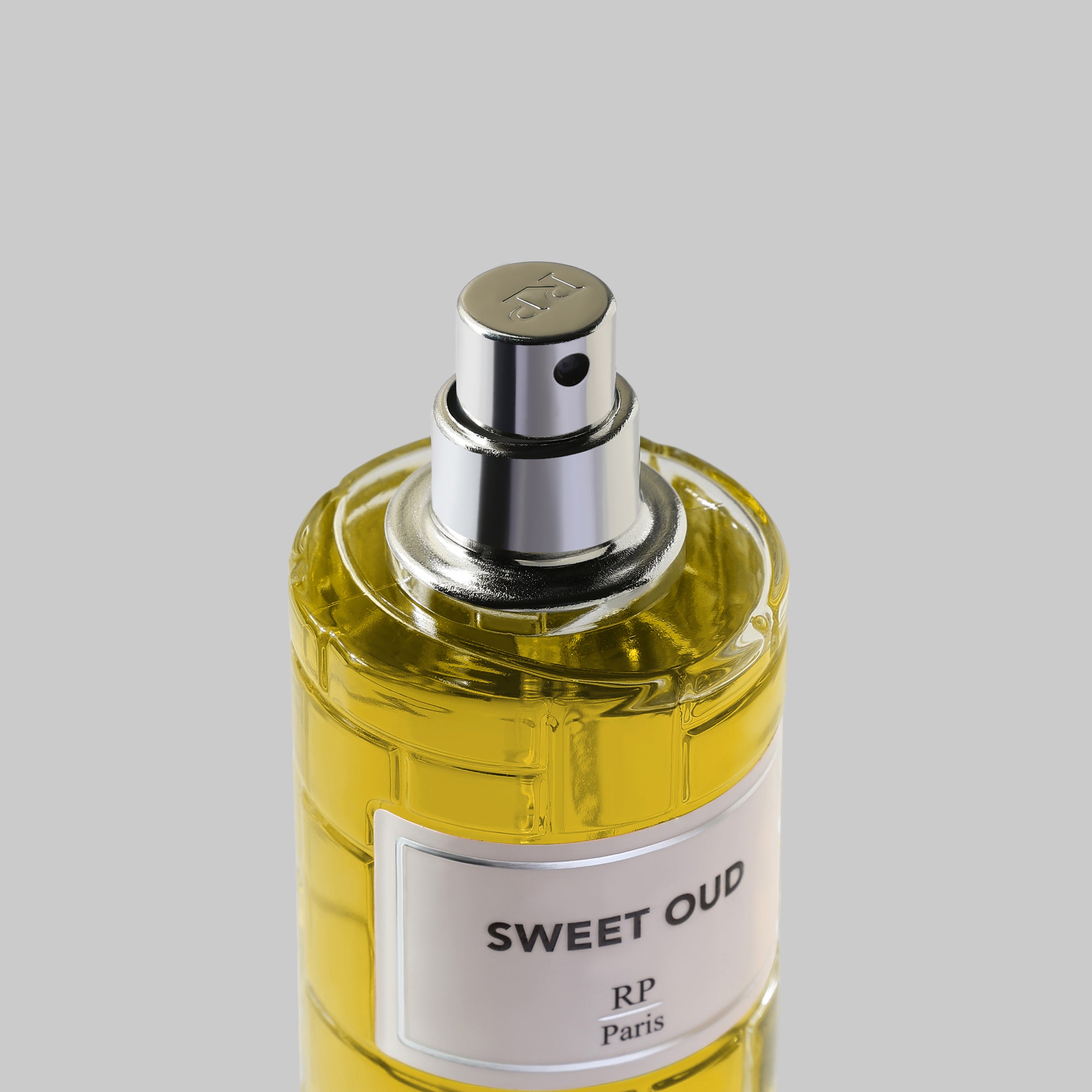 Perfume bottle labeled 'Sweet Oud' by RP Paris on a gray background