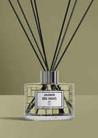 A reed diffuser bottle with black reeds, a clear glass body, and a white label reading 'JASMIN DES INDES R.F.