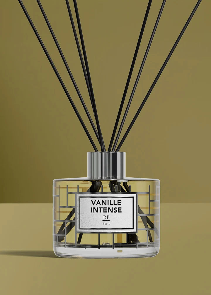 A reed diffuser bottle with black reeds, featuring a clear glass container with a white label that reads 'VANILLE INTENSE' and 'R.F.