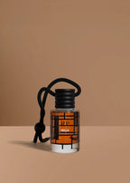 A small clear glass bottle with amber liquid and a black cord loop, labeled RP BELLA, set against a warm tan background.