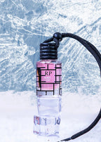 A small cylindrical perfume bottle labeled 'RP Bubble Gum' with pink liquid and a black geometric label, standing upright in a clear ice block against a snowy, icy blue background with a black cord attached at the top.