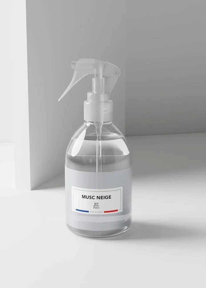 A clear glass spray bottle with a white trigger sprayer and a white label reading 'MUSC NEIGE' on a minimalist light gray background.