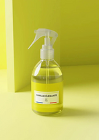 A clear spray bottle filled with pale yellow liquid, featuring a white trigger sprayer and a white label that reads 'VANILLE ÉLÉGANTE' with '24h Paris' below. The bottle is set against a minimalist lime green background.