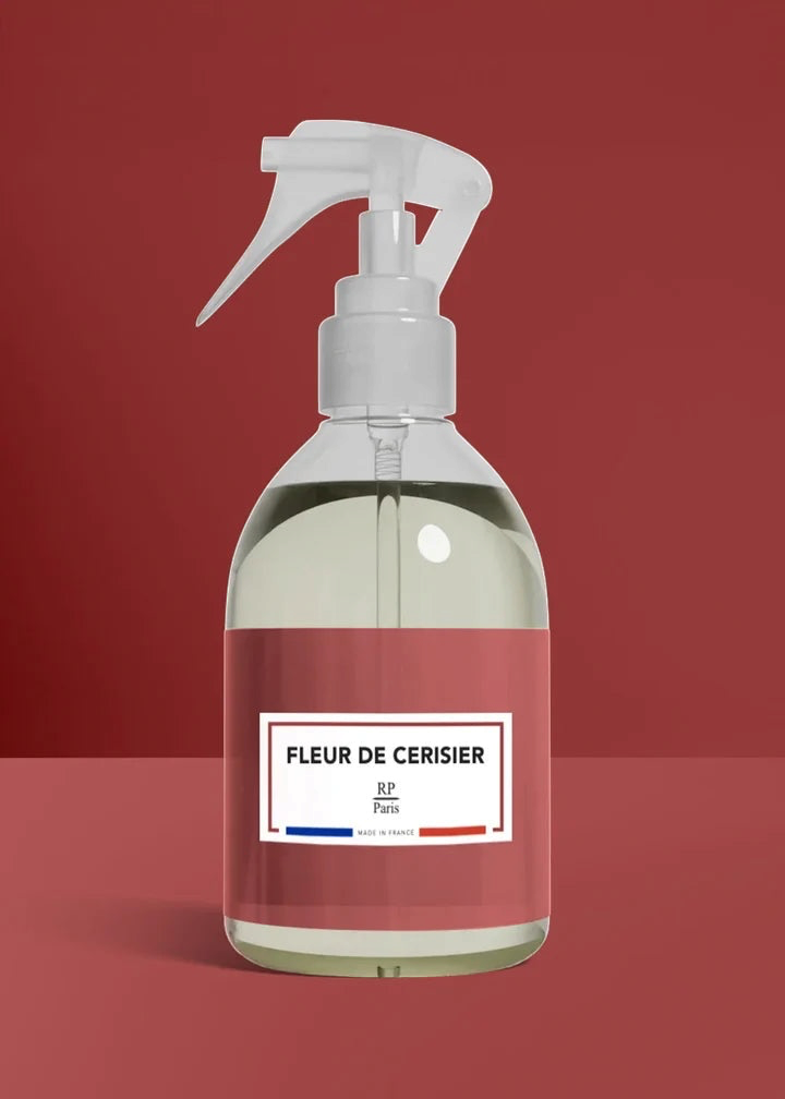 Clear spray bottle with a red label on a red background fleur de cerisier