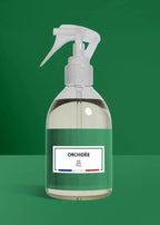 Clear spray bottle with a green label on a green background