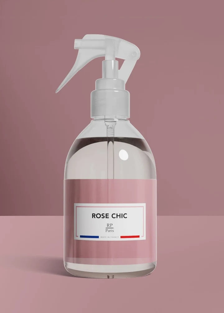 Clear spray bottle with a pink label on a pink background