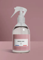 Clear spray bottle with a pink label on a pink background