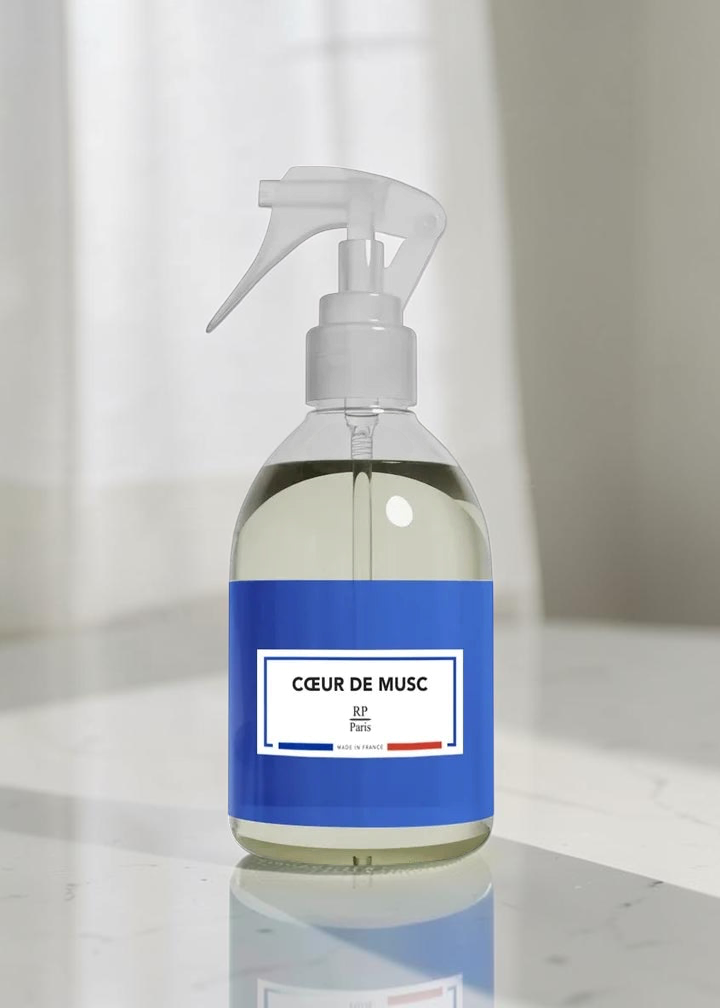A clear plastic spray bottle filled with pale yellow liquid, featuring a white trigger sprayer and a blue label with the text 'CŌEUR DE MUSC' and 'BF Paris'.