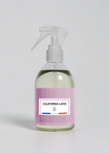 RP PARIS California Love scented fabric spray in a clear bottle with a light pink label and white trigger sprayer.